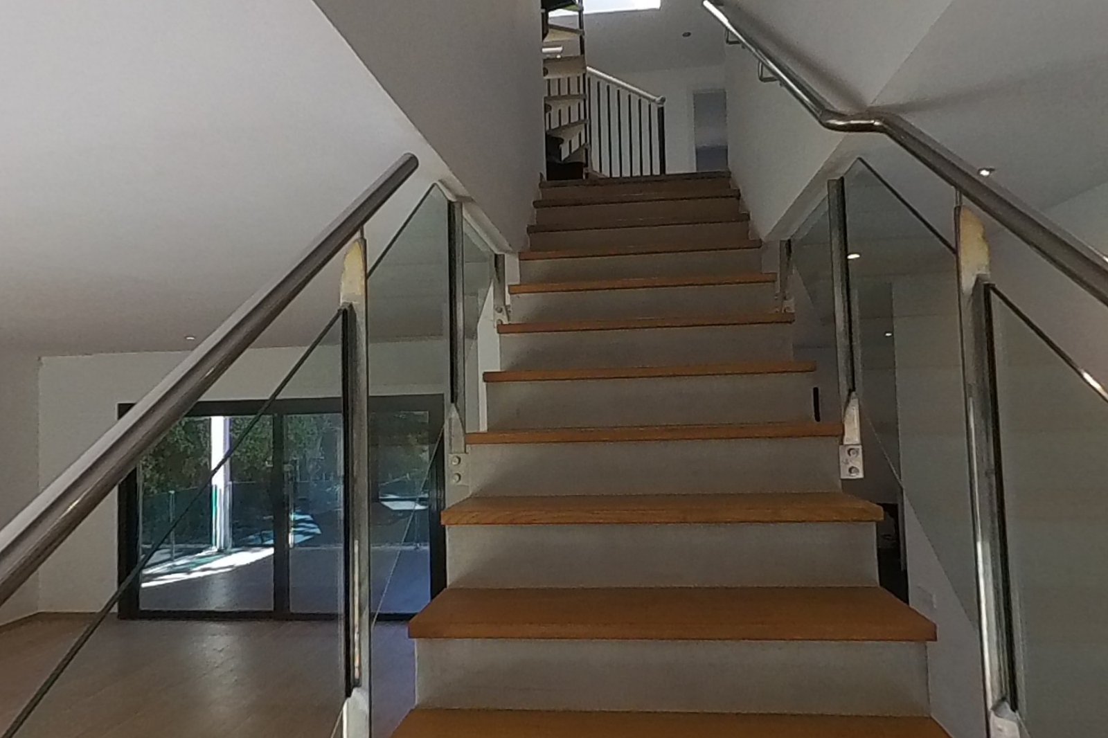 Escalera de peldaños de roble y barandilla de vidrio